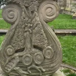 Stone carved with viking ship, in a graveyard overlooking the sea